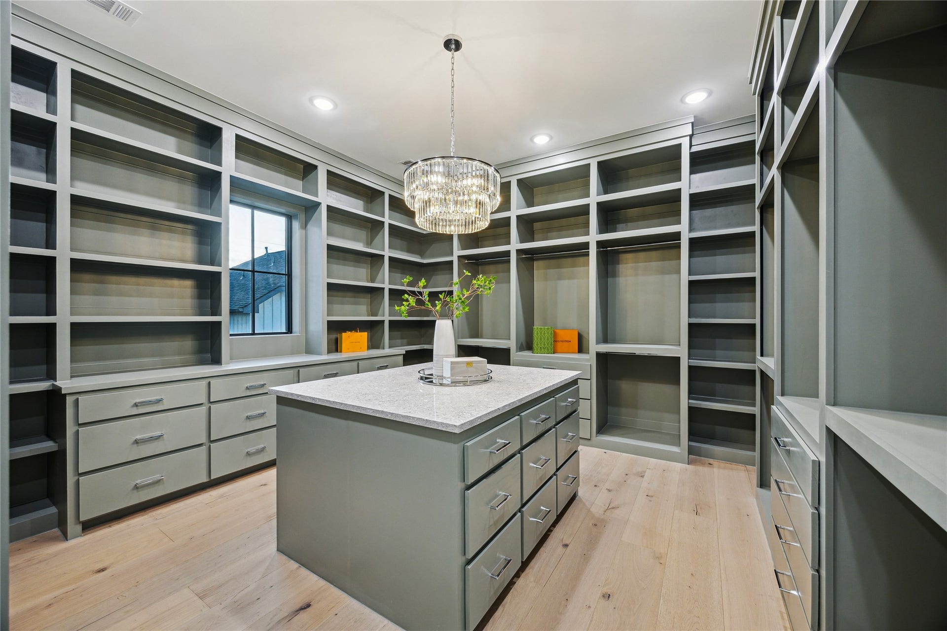 431 W 30th Street, Houston, TX 77018 Indulge in luxury with this master walk-in closet, featuring custom shelving, ample drawers, and a quartz-topped island, all highlighted by elegant lighting.