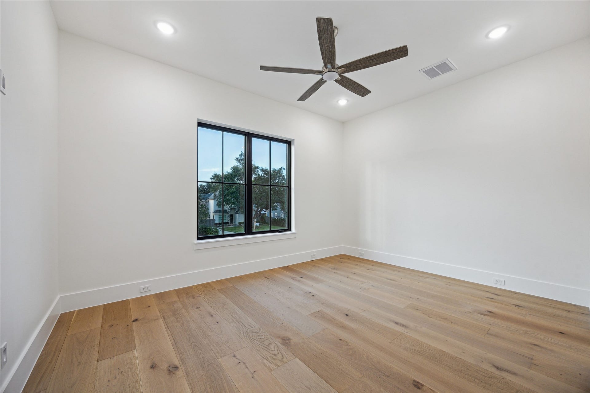 431 W 30th Street, Houston, TX 77018 This room features light hardwood floors, a large window offering natural light, and a modern ceiling fan. The walls are painted white, creating a bright and airy atmosphere.