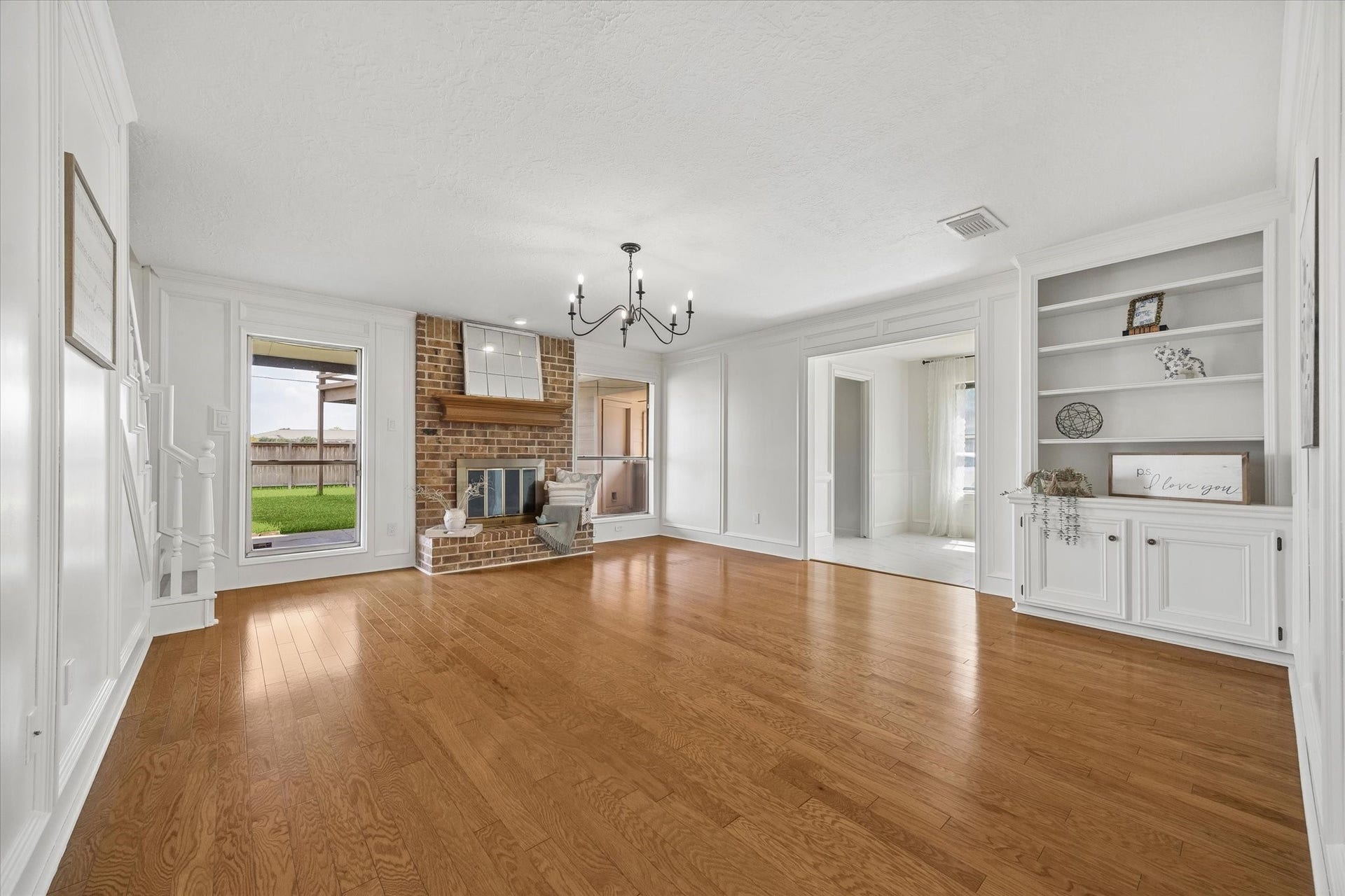 110 Shadow Wood Drive, Sugar Land, TX 77498 The cozy living room featuring elegant hardwood floors, a brick fireplace, and built-in shelving, which can be used as small work space.