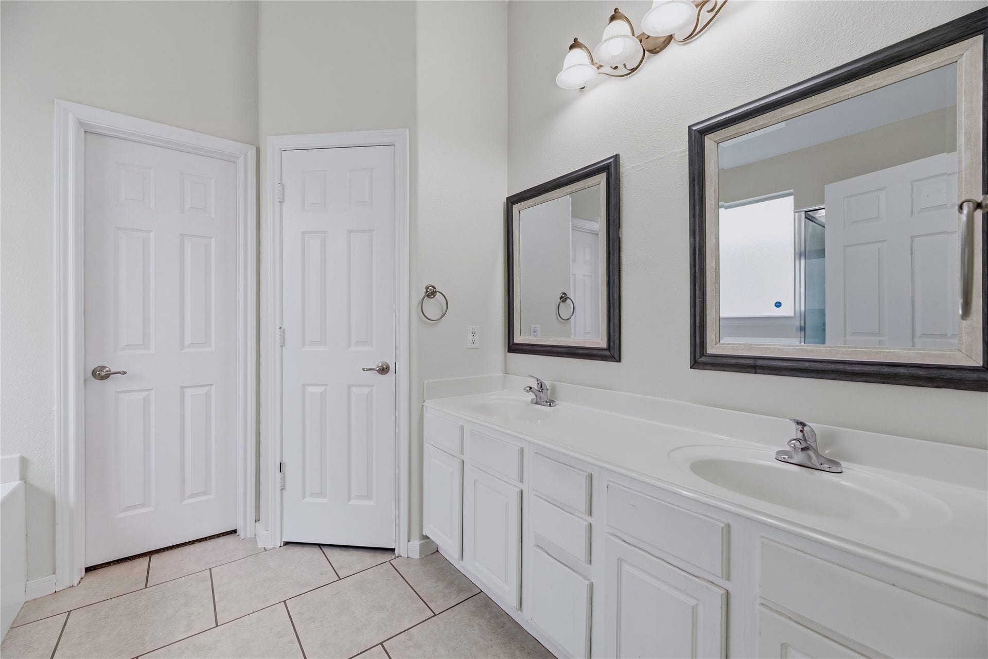 Two sinks and separate mirrors make it easier to share the primary vanity, while drawers and cabinets offer space for everyday bath essentials.