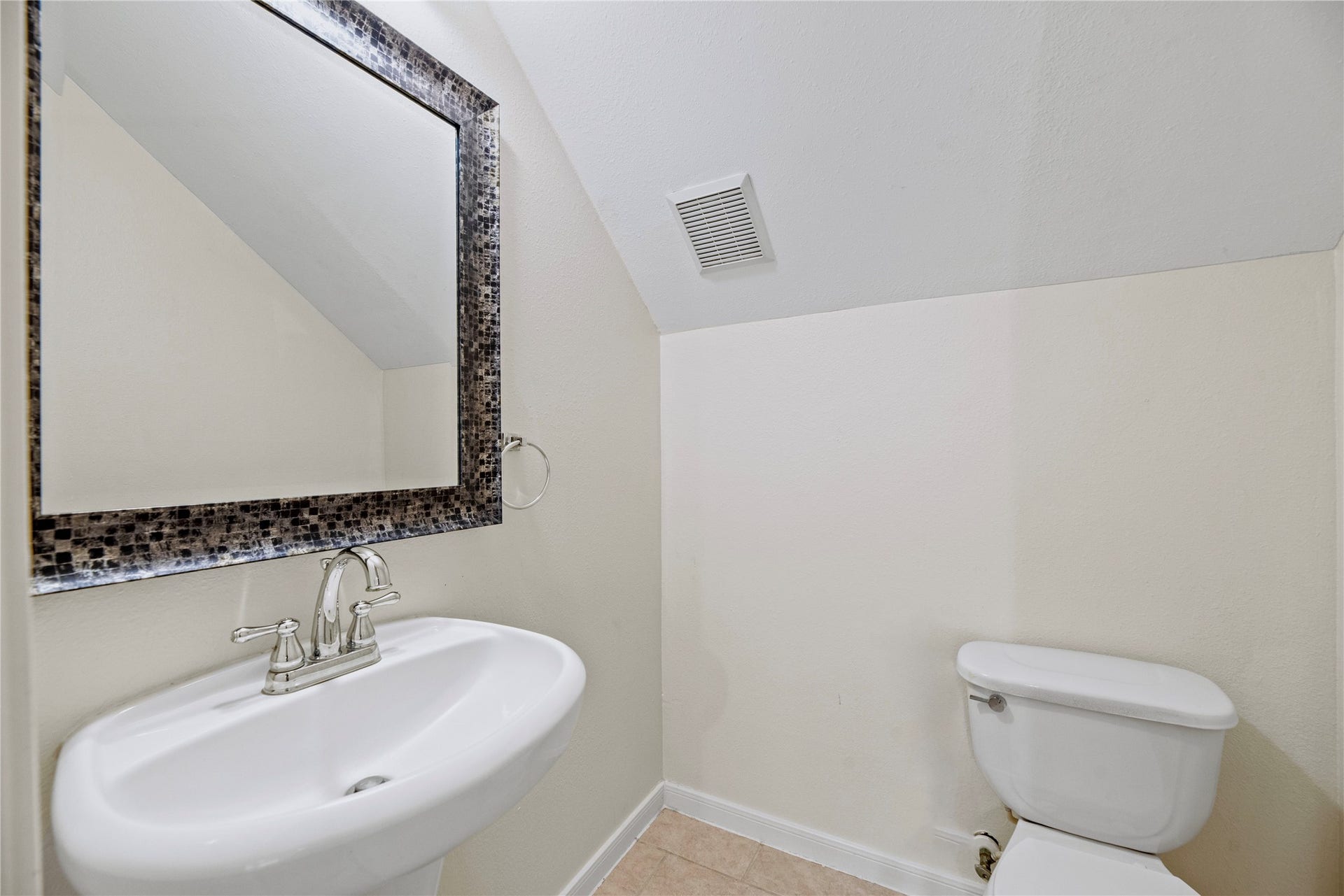 A pedestal sink and framed mirror give the half bath a simple, practical layout, adding a separate spot for guests away from the full bathrooms.