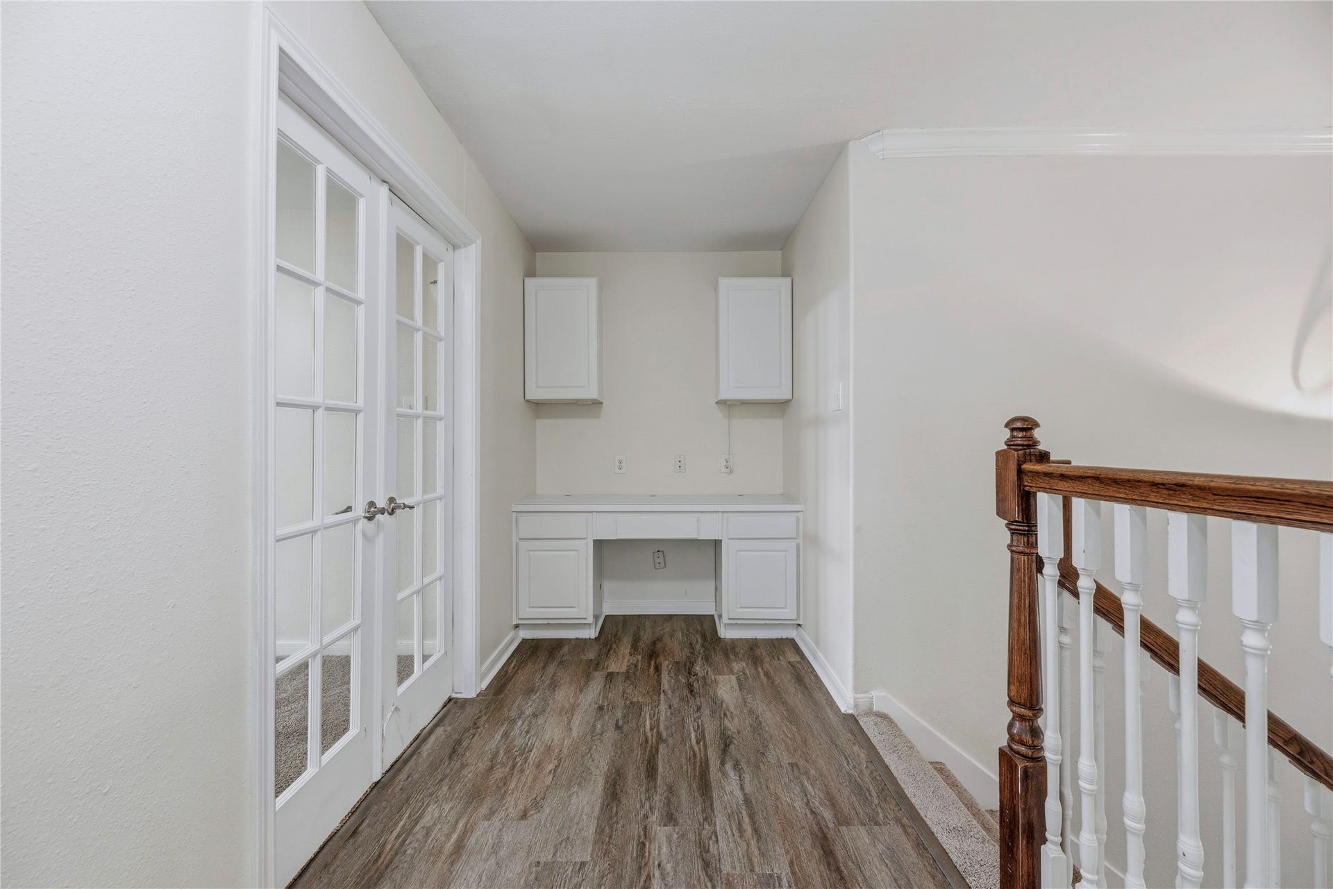 A built-in desk and upper cabinets create a ready spot for a laptop or household organization beside the upstairs French-door room.