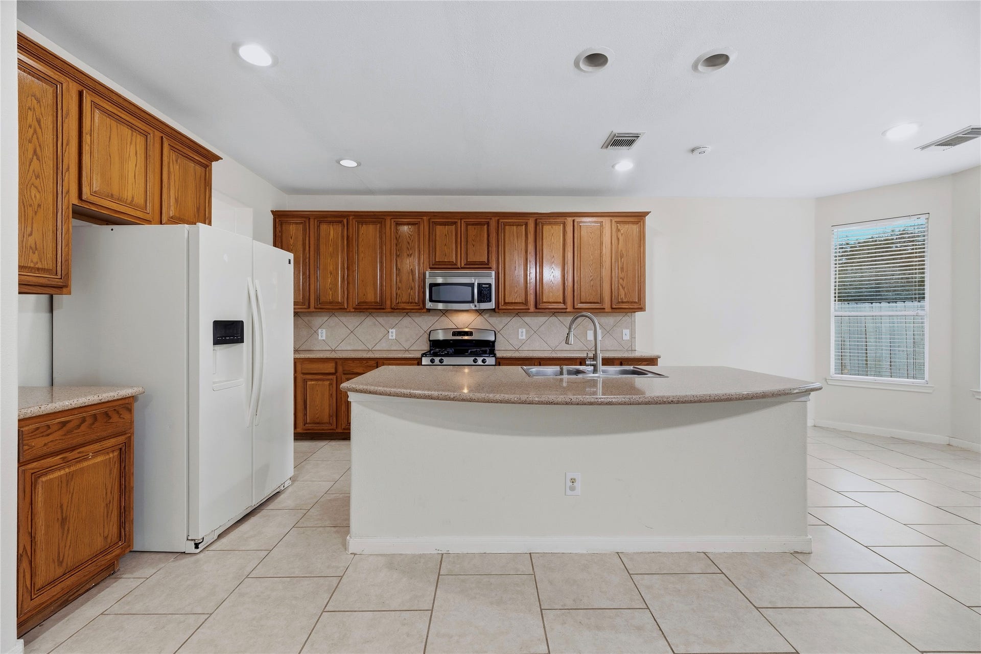 The central island adds a generous work surface, while cabinets along the back wall help keep kitchen essentials close to the cooking area.