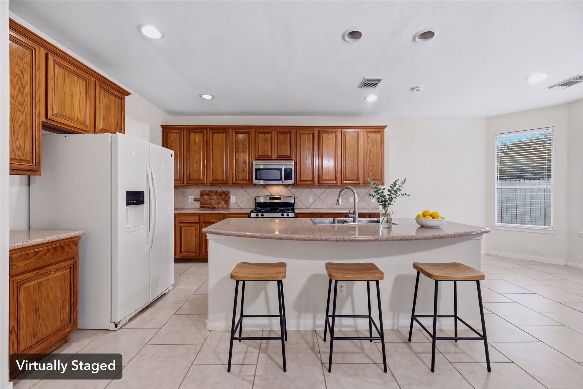 Virtually staged to illustrate casual seating at the island and its connection to the surrounding kitchen. Furniture shown is digital.