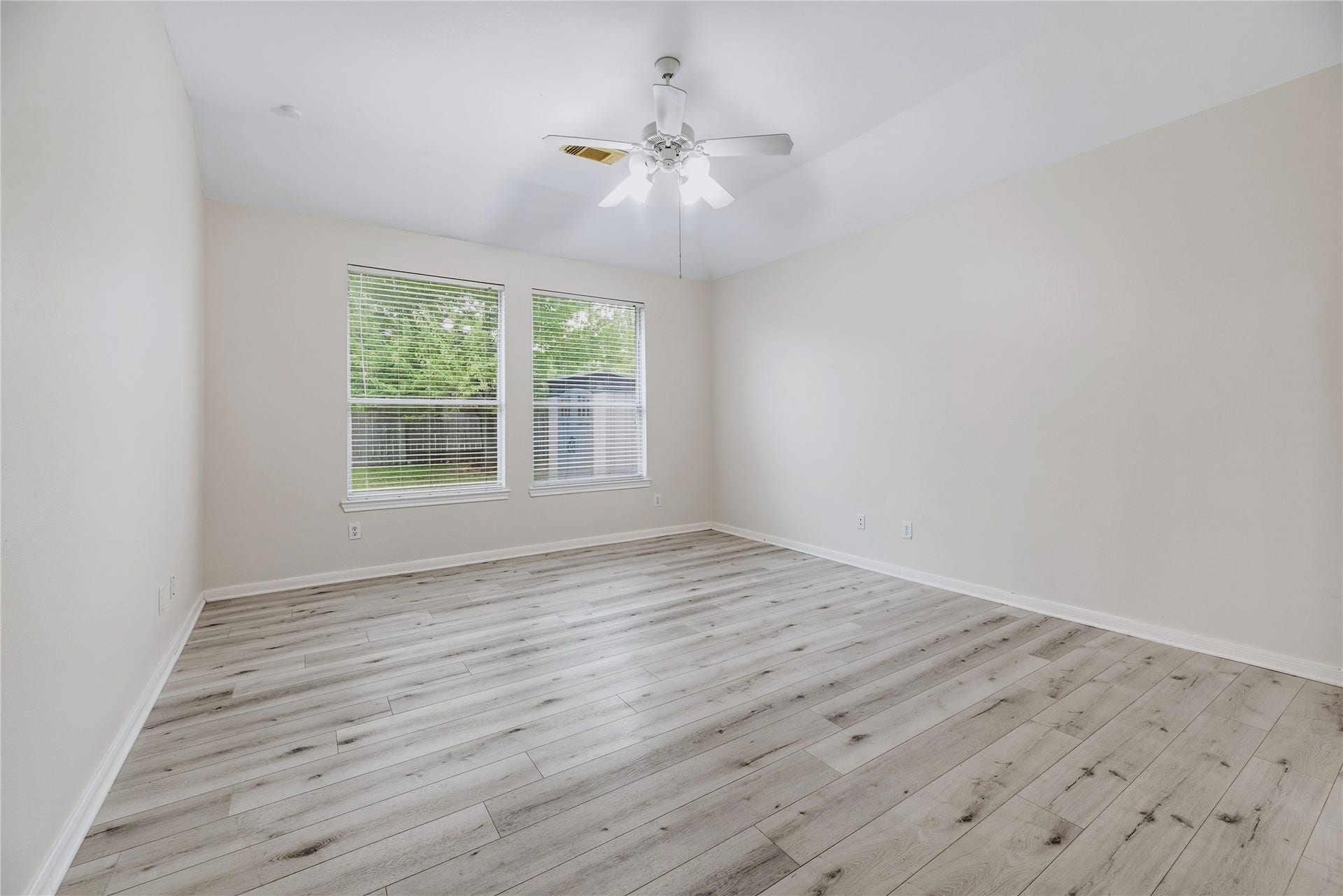 The unfurnished primary bedroom shows the available floor space, paired windows and ceiling fan, so you can picture how your own furniture will fit.
