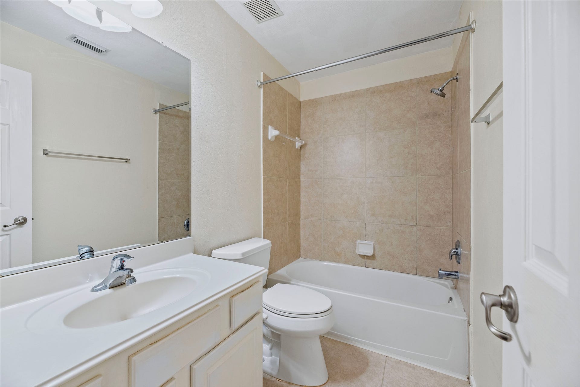 The hall bath brings together a vanity with cabinet storage and a tub-shower combination, creating a practical full-bath setup for the secondary rooms.