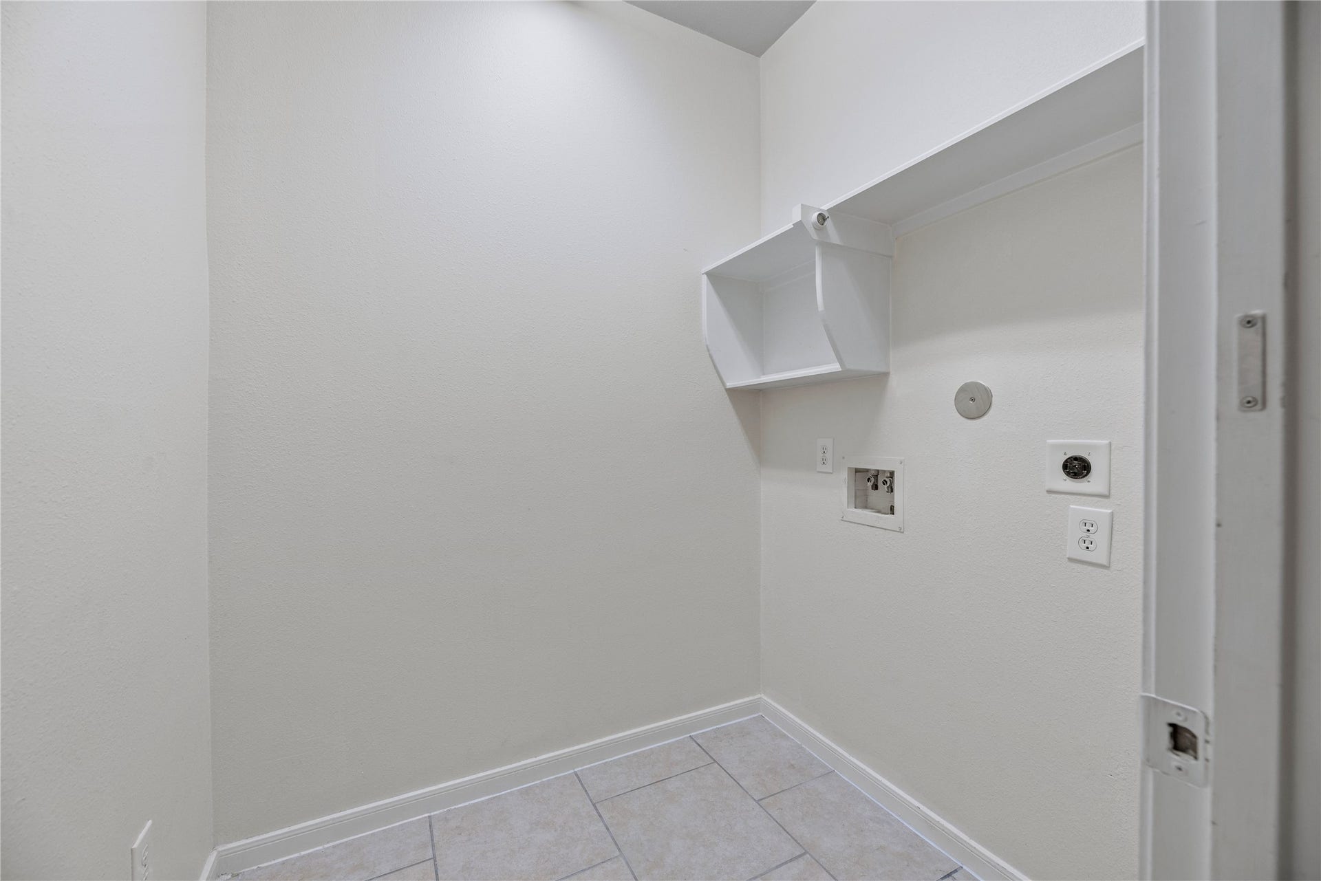A dedicated utility room keeps laundry in its own space, with washer and dryer connections, an overhead shelf and a hanging rod for organization.