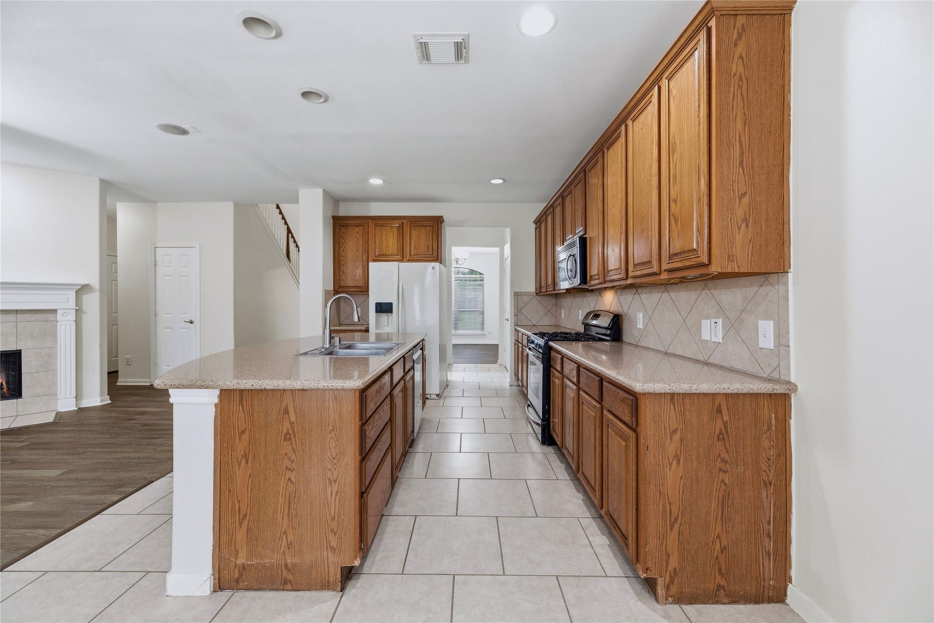 This view shows the aisle between the island and cooking wall, plus the kitchen storage and its open connection to the main living space.