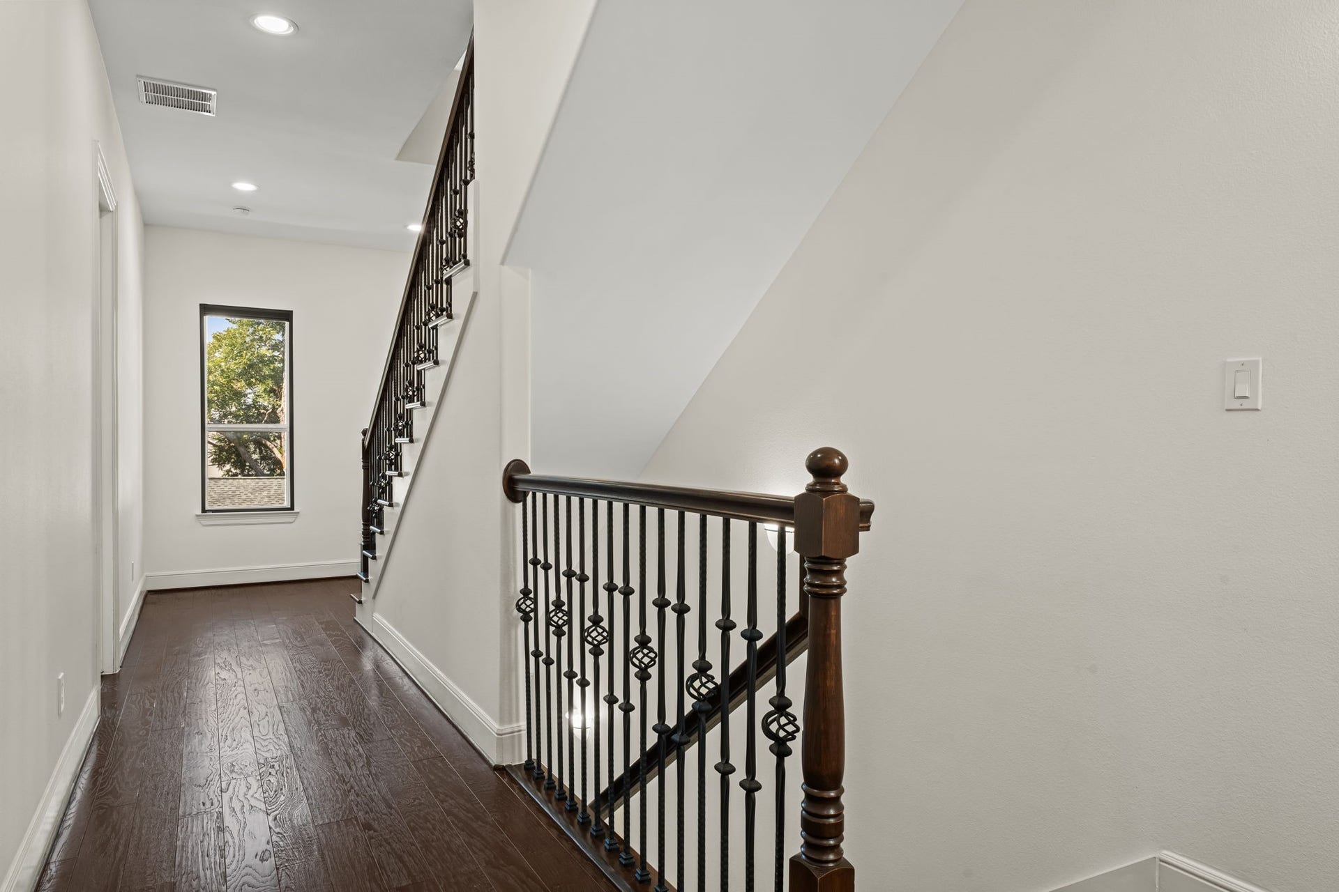 The stair landing is brightened by natural light and accented with classic iron balusters. A well-proportioned transition connects the home's private upper levels.
