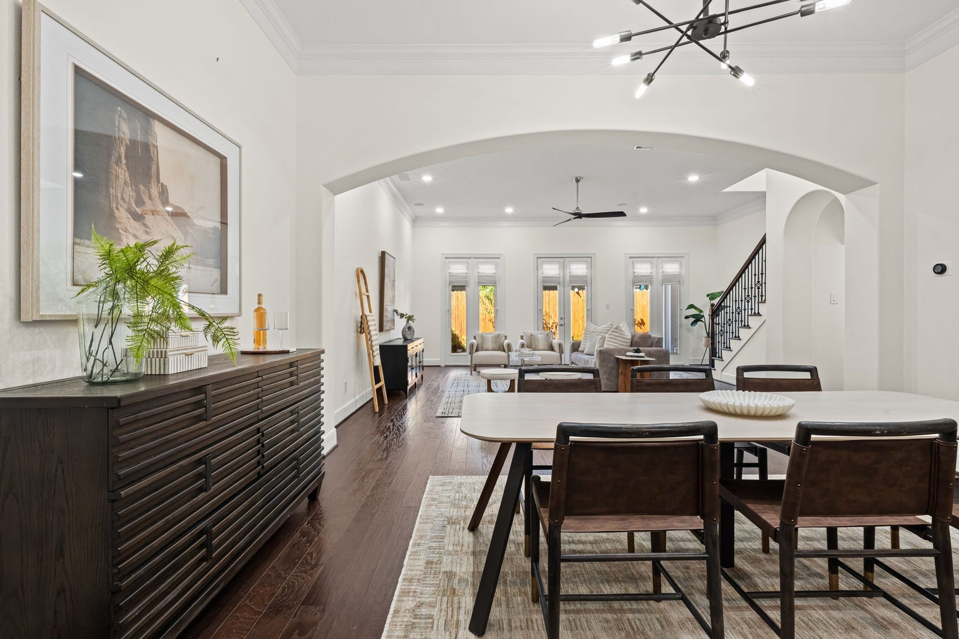 The first floor unfolds into an expansive open-concept setting with high ceilings and wood flooring. Clear sightlines between the kitchen, dining area, and living room enhance the home's sense of scale.