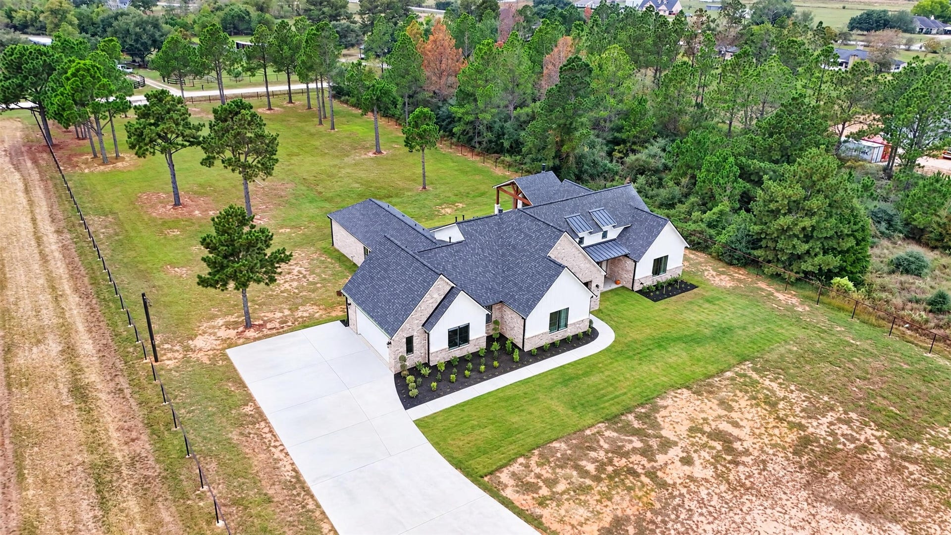 35851 Pineridge Road, Waller, TX 77484 A drone angle captures the home's varied rooflines, driveway, broad lawn, and tree-lined acreage.