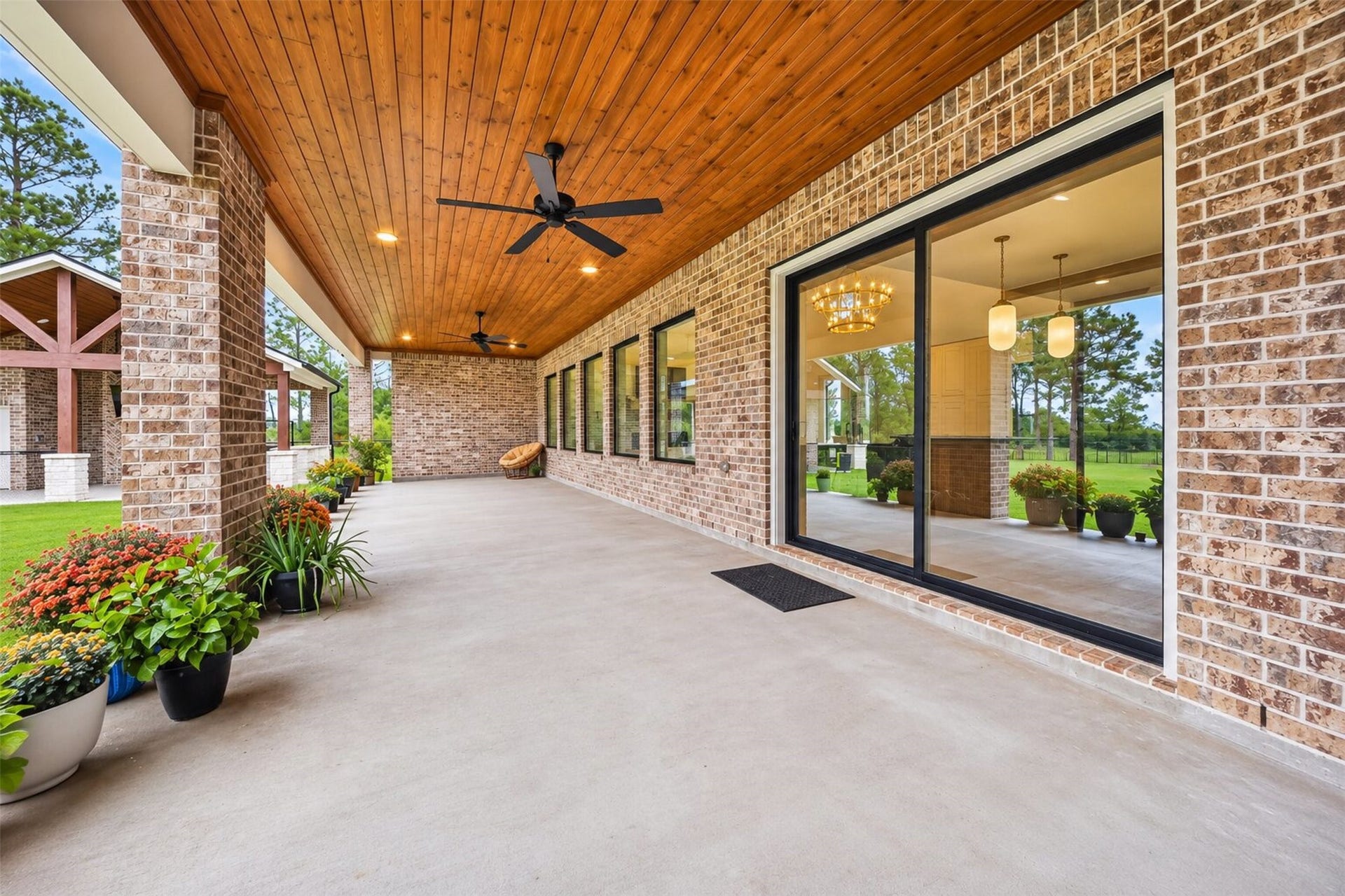 35851 Pineridge Road, Waller, TX 77484 The covered patio follows the home's brick rear wall, with wide windows and glass doors connecting the interior to the yard.