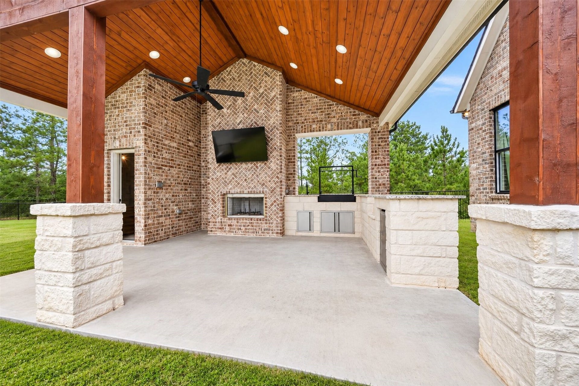 35851 Pineridge Road, Waller, TX 77484 Timber posts frame the covered outdoor kitchen, where a brick fireplace and stone counters extend the home's entertaining space.