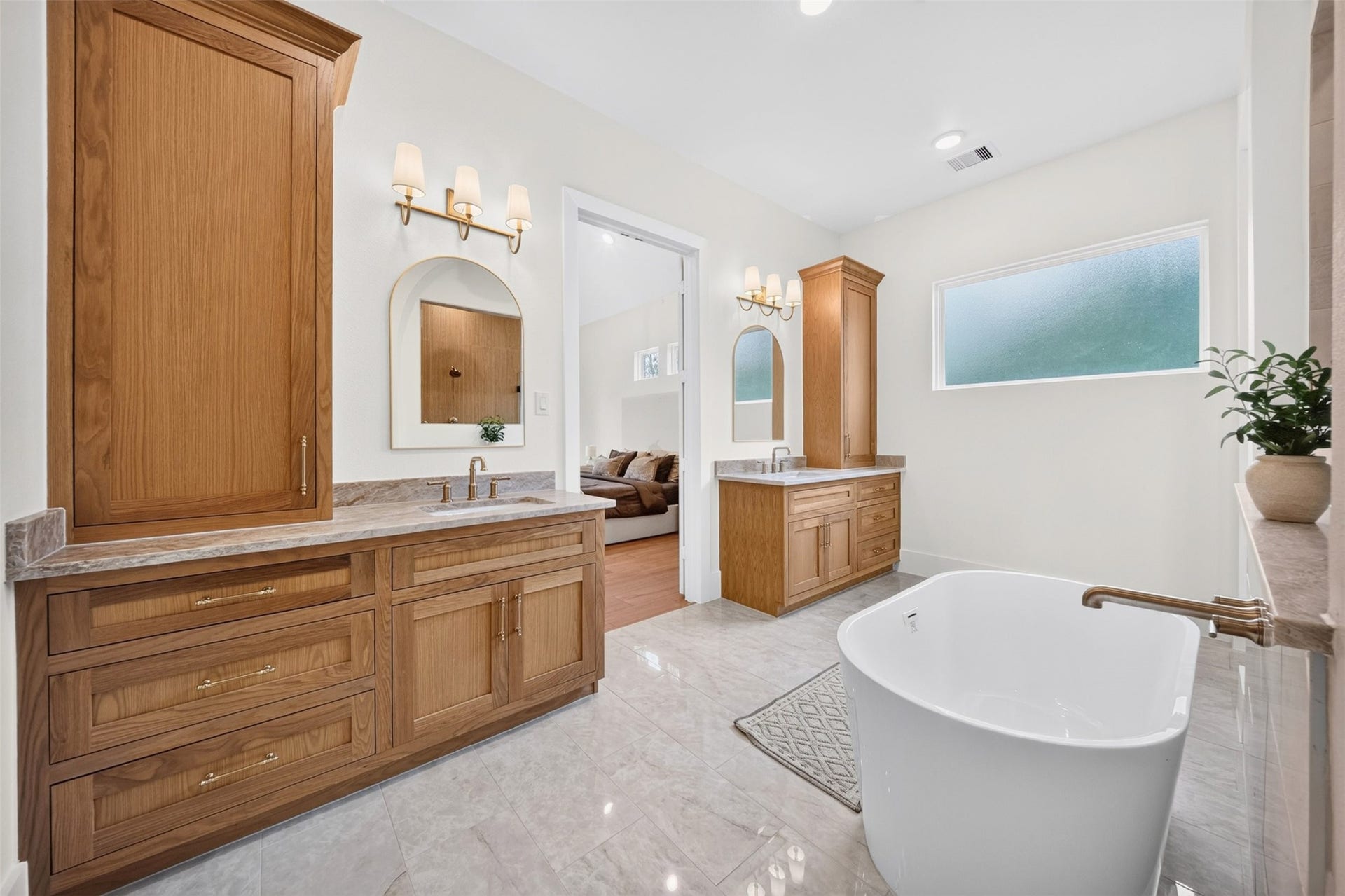 35851 Pineridge Road, Waller, TX 77484 The primary bath centers on a freestanding tub between dual wood vanities, with pale tile and a wide window bringing in natural light.