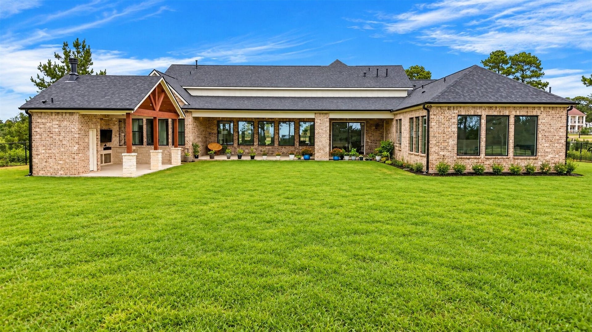 35851 Pineridge Road, Waller, TX 77484 The rear brick elevation opens onto the covered patio, where timber framing shelters the built-in outdoor kitchen.