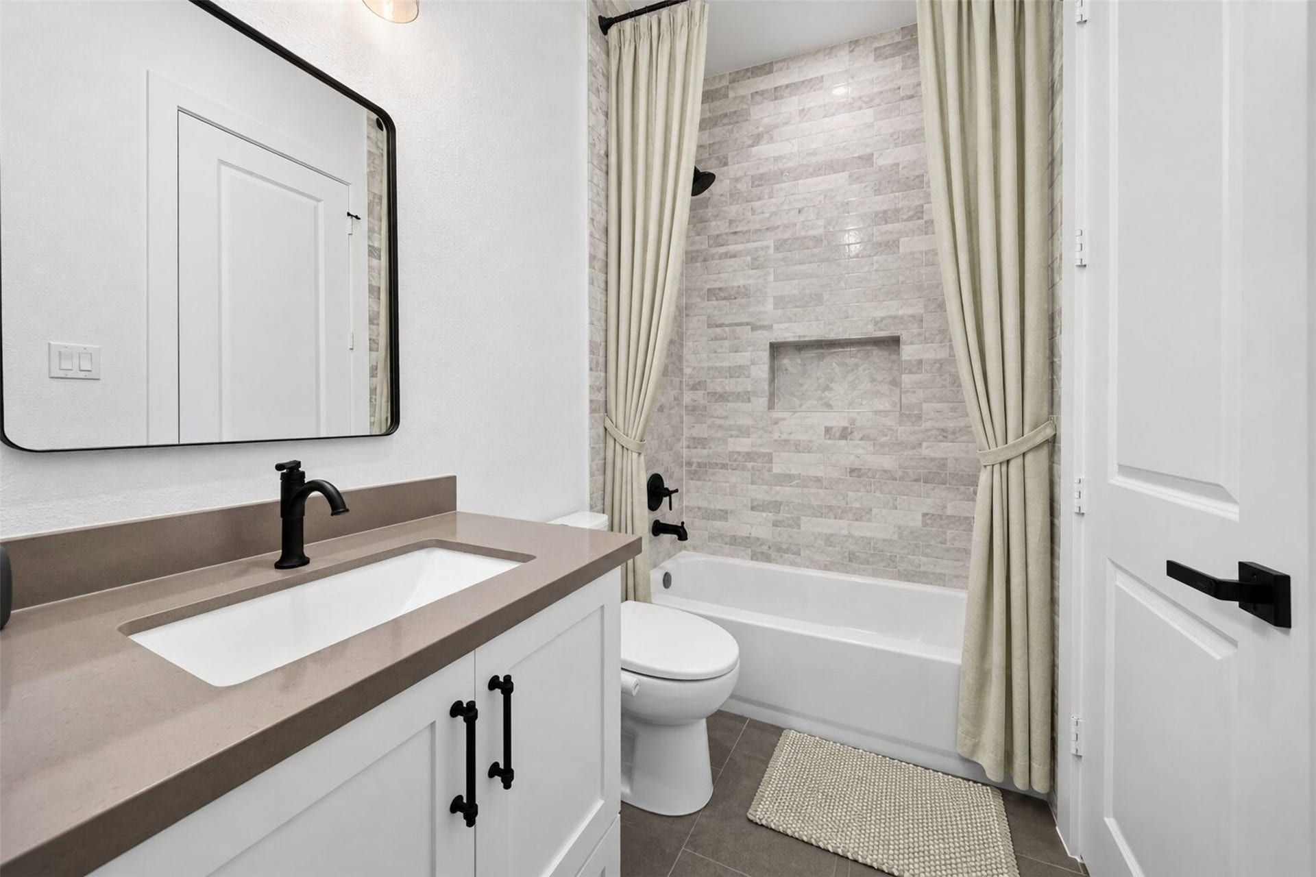 35851 Pineridge Road, Waller, TX 77484 Light marble-look tile wraps the tub and shower, paired with a pale vanity and dark fixtures for a clean, modern finish.