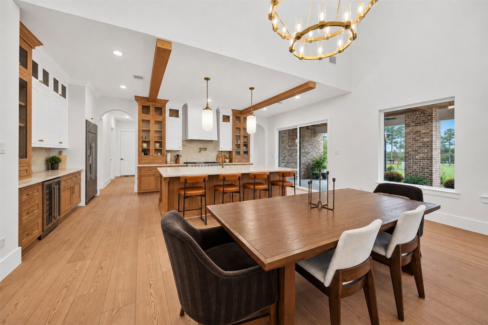 35851 Pineridge Road, Waller, TX 77484 The kitchen opens to the dining area, with a stone island and warm wood cabinetry beneath exposed beams that tie both spaces together.