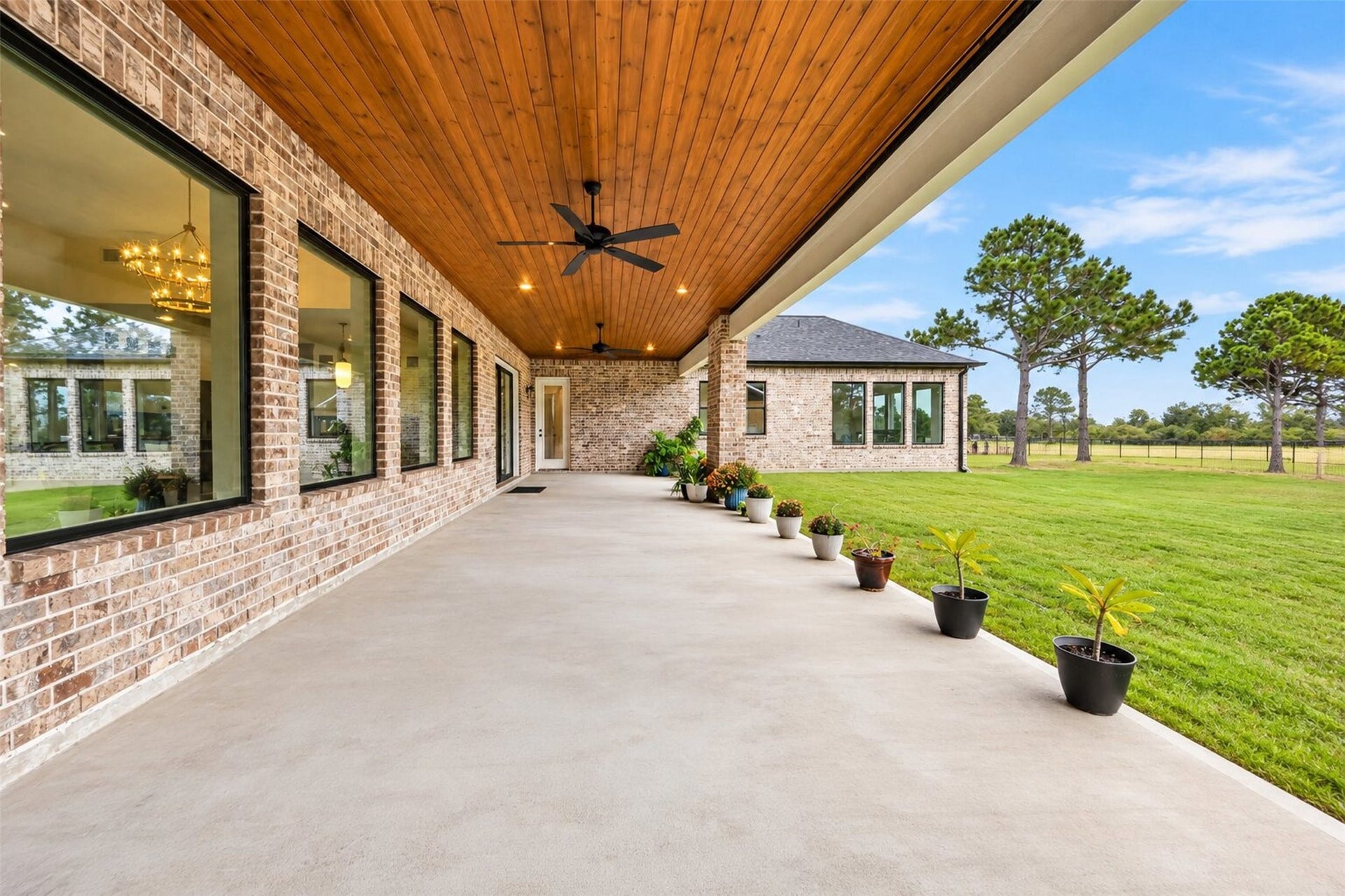 35851 Pineridge Road, Waller, TX 77484 A long covered patio runs along the rear of the home, with a wood-plank ceiling and open views across the backyard lawn.