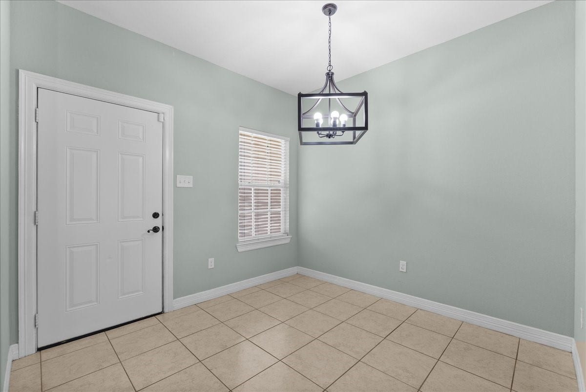 15531 Maple Street, Santa Fe, TX 77517 A statement chandelier marks a defined dining space just off the kitchen, framed by a nearby window and a convenient door leading out to the yard. Tile flooring, crown molding, and fresh neutral paint carry the home's finishes through to this corner of the main living area.