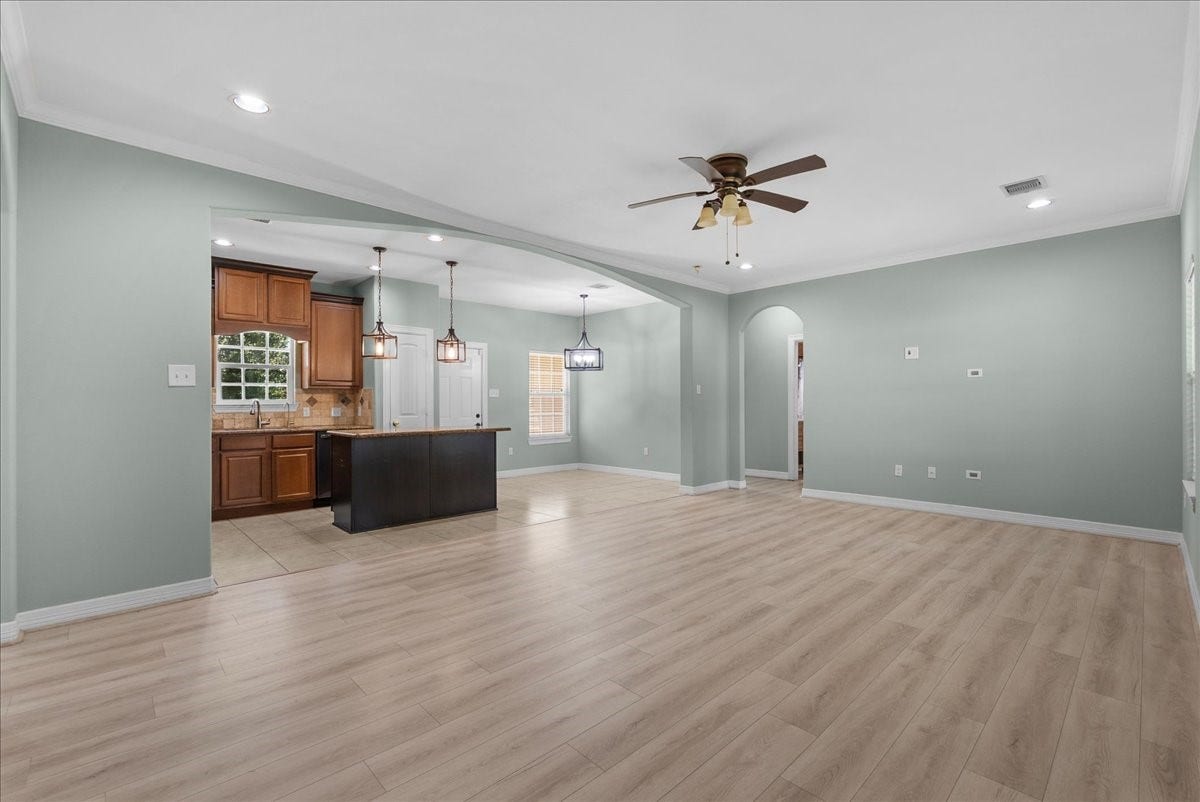 15531 Maple Street, Santa Fe, TX 77517 An expansive open-concept floor plan links the living space to the kitchen through a wide archway, with pendant lighting over the island and a chandelier marking a defined dining area.