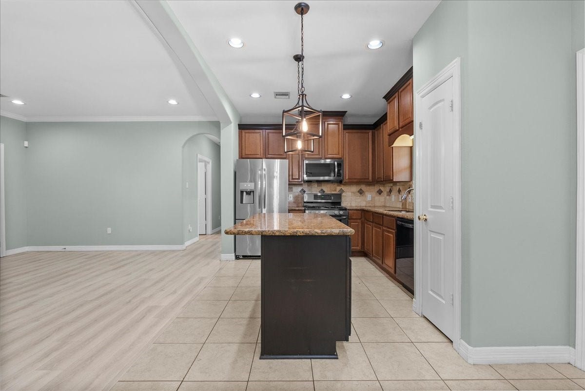 15531 Maple Street, Santa Fe, TX 77517 A pantry door sits just off the kitchen, and the tile-to-wood flooring transition marks a clean division between the kitchen and the adjoining living space.
