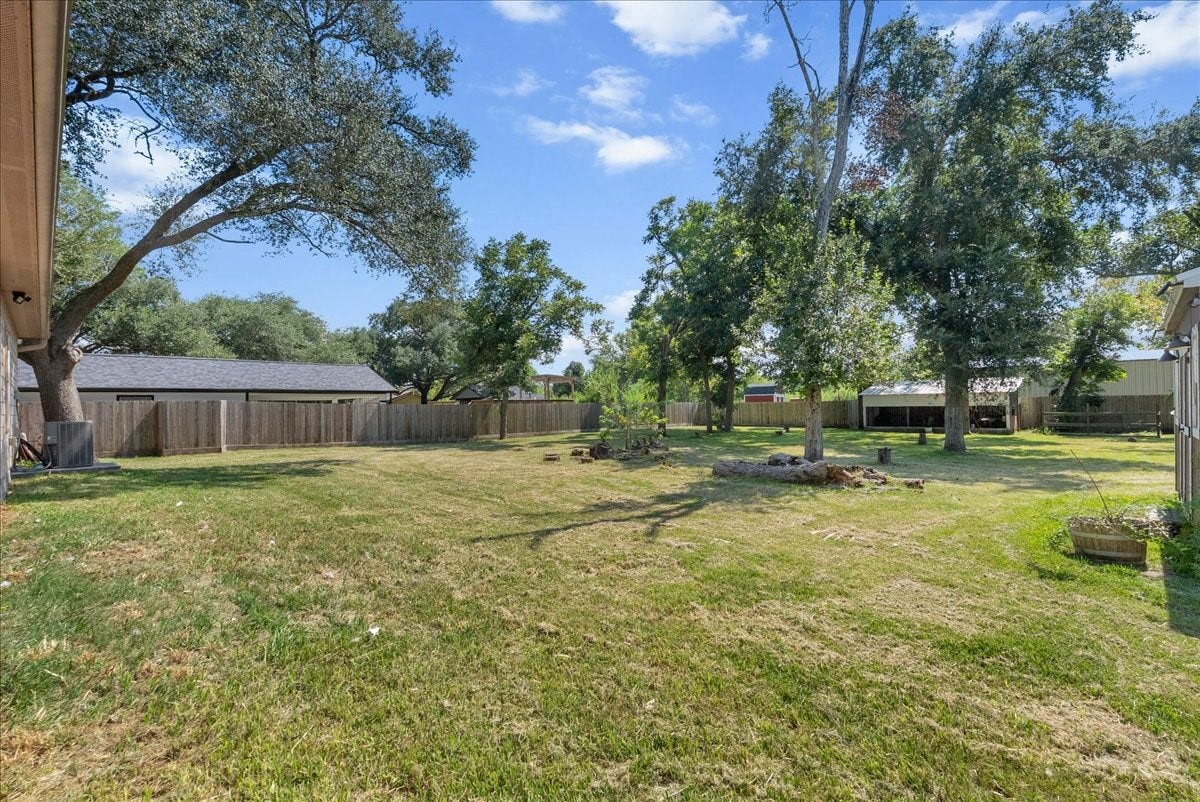 15531 Maple Street, Santa Fe, TX 77517 The fully fenced backyard offers a wide, open expanse of grass shaded by mature oak trees.