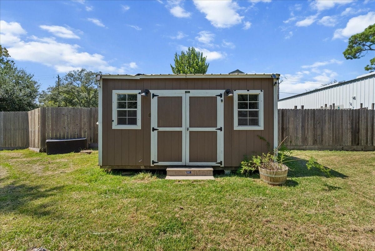 15531 Maple Street, Santa Fe, TX 77517 The hardwired storage building offers double doors, windows on either side for natural light, and wiring already in place, ready to be a workshop, hobby space, or private retreat.