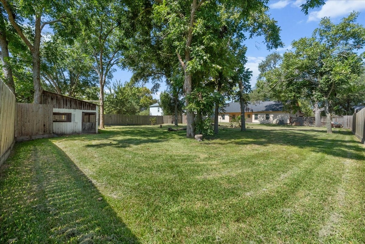 15531 Maple Street, Santa Fe, TX 77517 The fenced half-acre lot really shows here, with a deep, wide-open stretch of yard reaching well past the home's footprint. A canopy of mature trees scattered across the grounds keeps the space shaded without crowding it, leaving plenty of open acreage for a garden, play area, or future outdoor project.