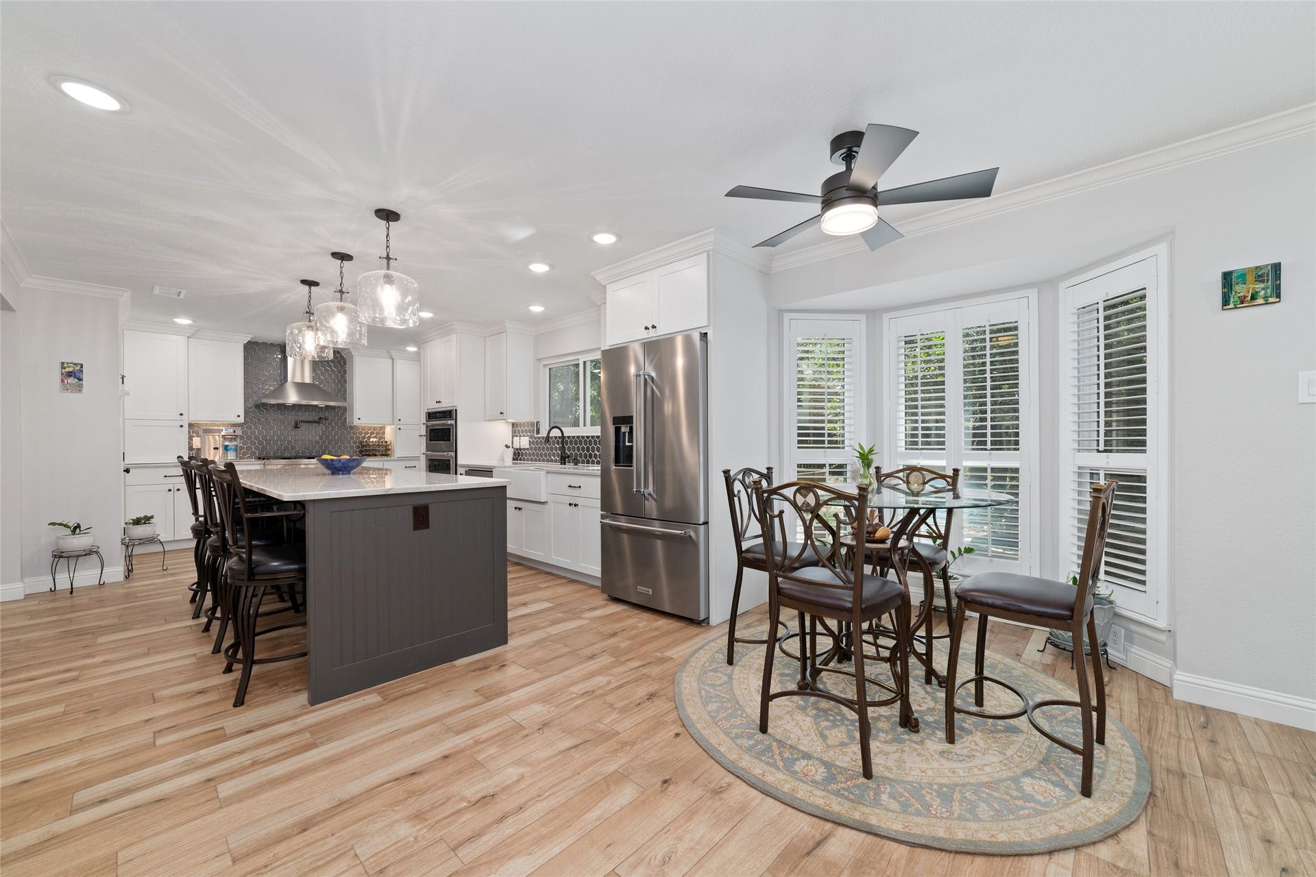 218 E Rainbow Ridge Circle, The Woodlands, TX 77381 Bright and modern kitchen with a spacious island, elegant pendant lighting, and stainless steel appliances. The adjacent breakfast nook opens seamlessly from the kitchen and features a cozy dining area with large bay windows and plantation shutters, allowing plenty of natural light.