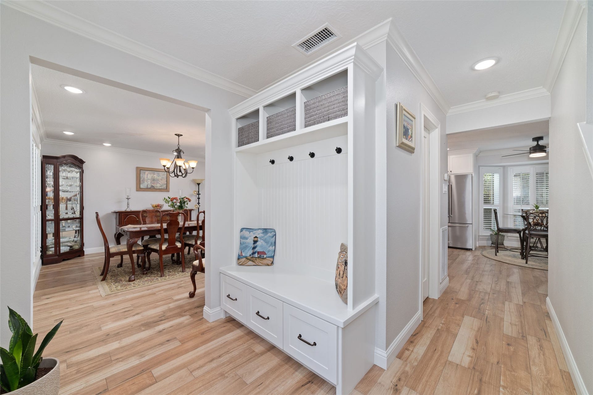 218 E Rainbow Ridge Circle, The Woodlands, TX 77381 Bright and inviting hallway with built-in storage bench leads to a cozy dining area and modern kitchen, featuring timeless solid surface flooring throughout.