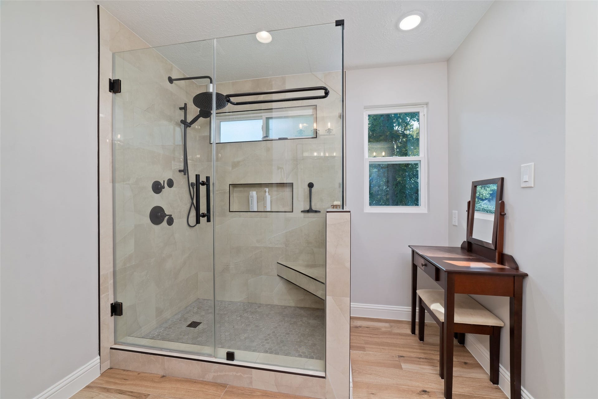 218 E Rainbow Ridge Circle, The Woodlands, TX 77381 Luxurious bathroom featuring a spacious glass-enclosed shower with elegant fixtures, complemented by a cozy area with natural light.