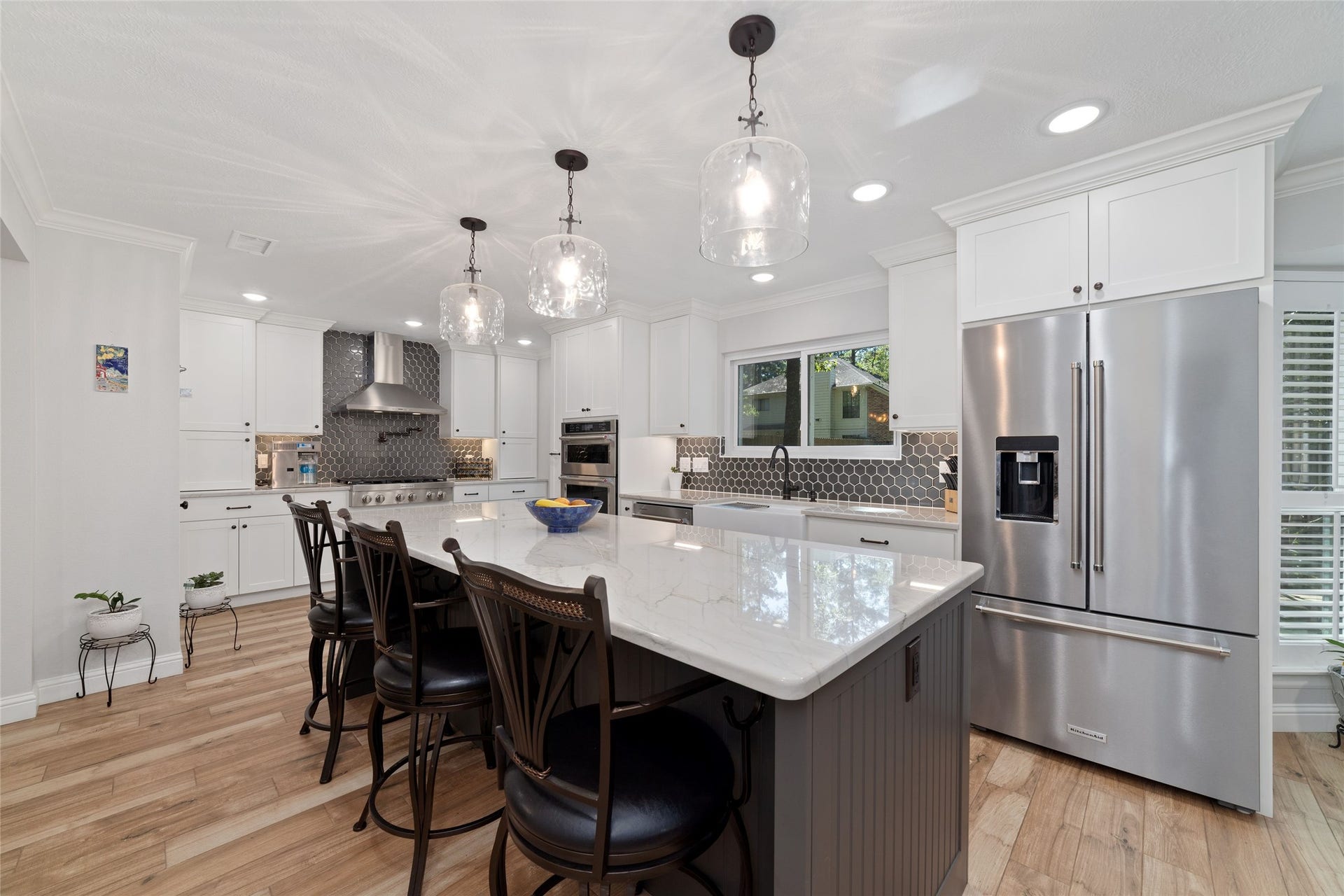 218 E Rainbow Ridge Circle, The Woodlands, TX 77381 Spacious kitchen featuring a large island with elegant pendant lighting, stainless steel appliances, and stylish backsplash.
