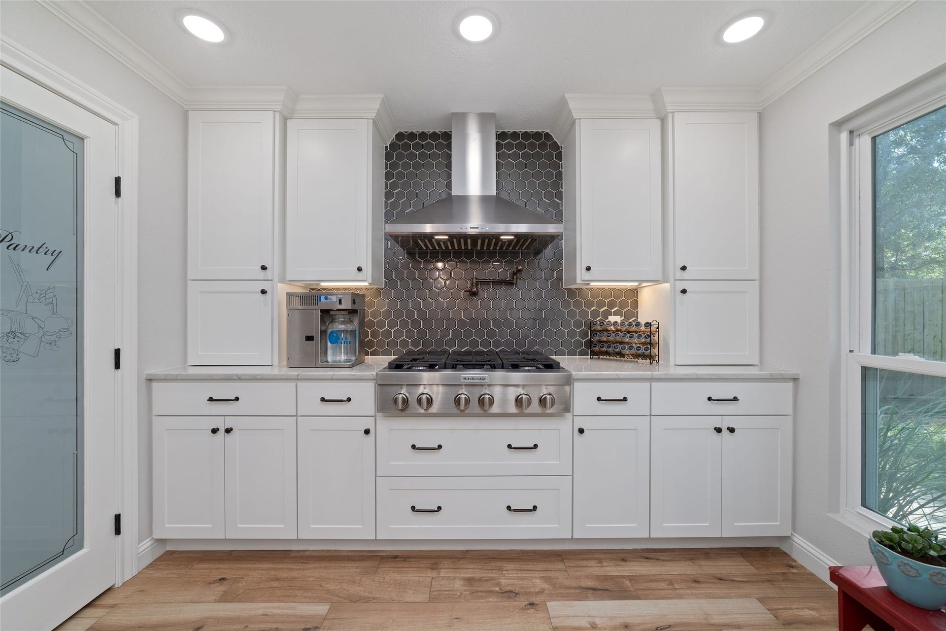 218 E Rainbow Ridge Circle, The Woodlands, TX 77381 Kitchen features white Shaker-style cabinetry, a sleek 6 burner gas range, and even a pot filler!