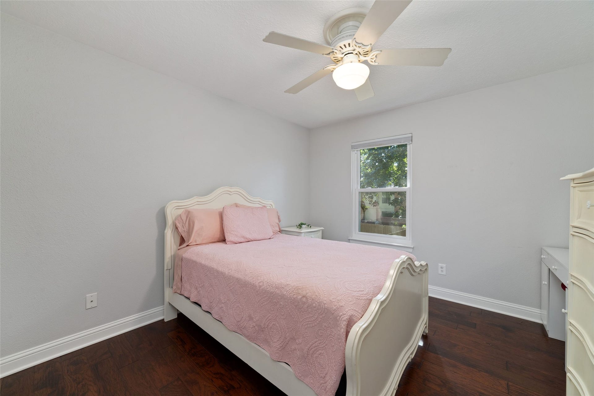 218 E Rainbow Ridge Circle, The Woodlands, TX 77381 Bedroom 4 is brightened by natural light from a window, highlighting the rich, dark wood flooring.