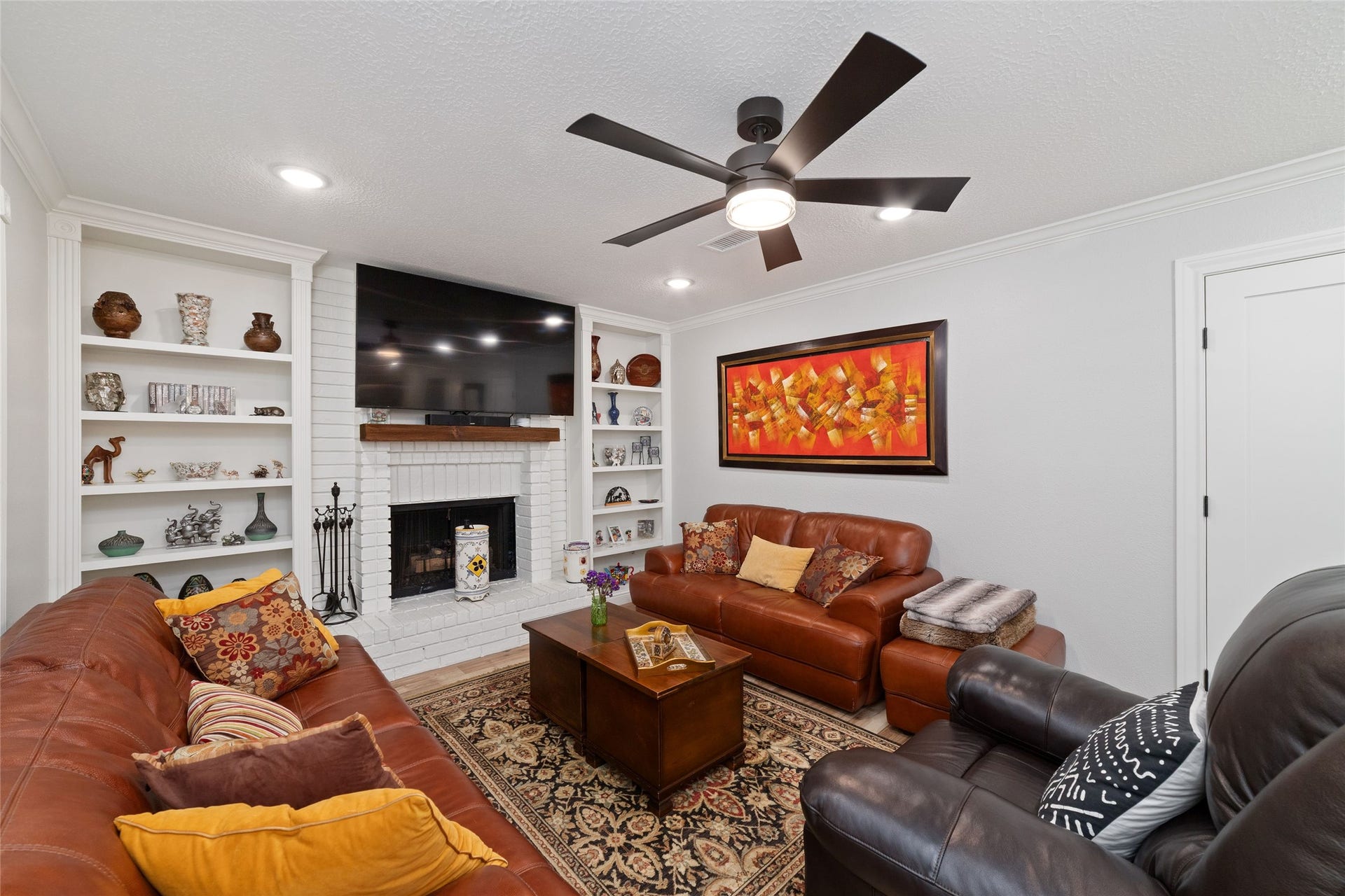 218 E Rainbow Ridge Circle, The Woodlands, TX 77381 Cozy living room with a gas-log fireplace and built-in shelving, perfect for relaxation and entertainment.