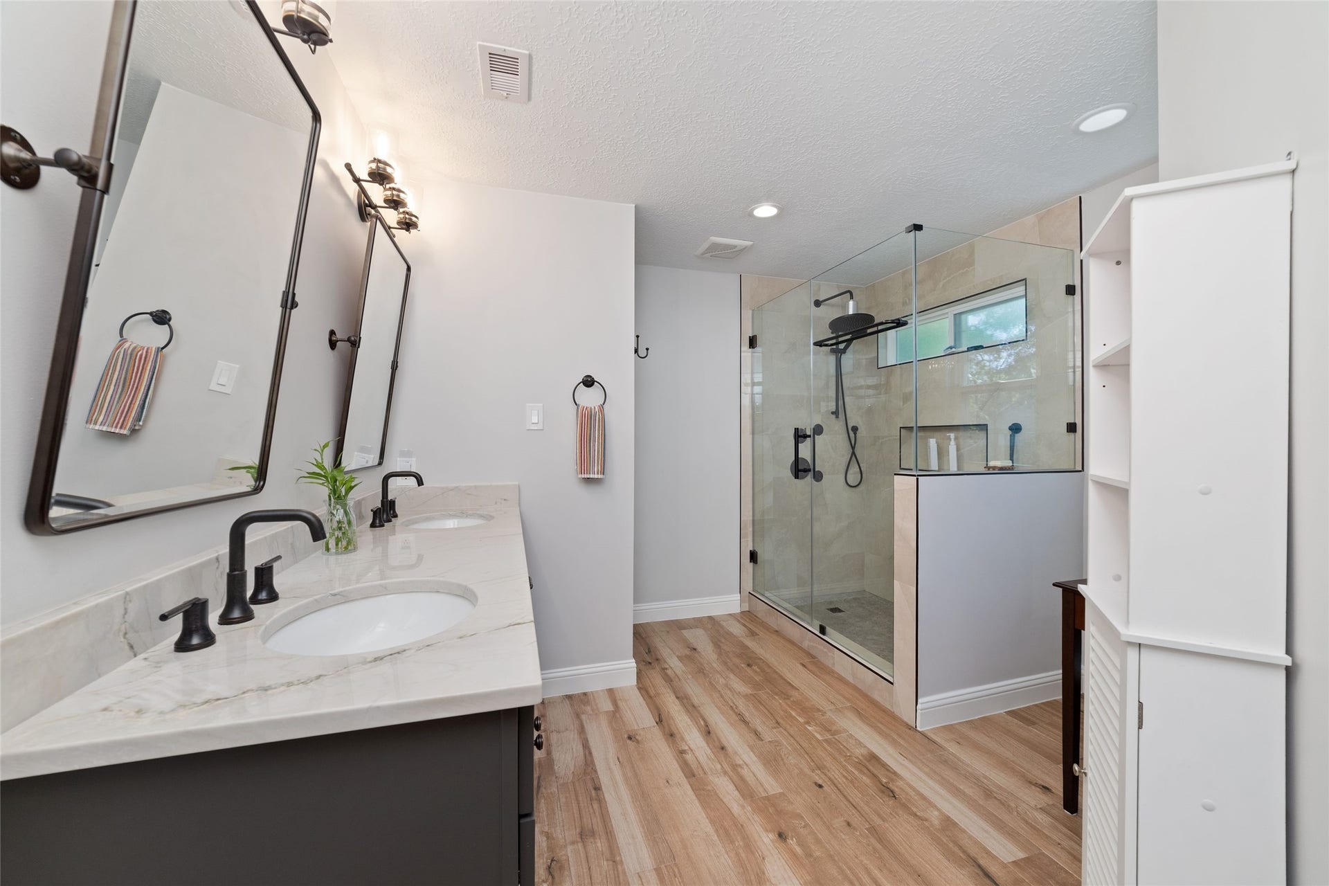 218 E Rainbow Ridge Circle, The Woodlands, TX 77381 Elegant bathroom featuring a double vanity with modern fixtures, a spacious glass-enclosed shower, and light flooring for a warm, inviting atmosphere.
