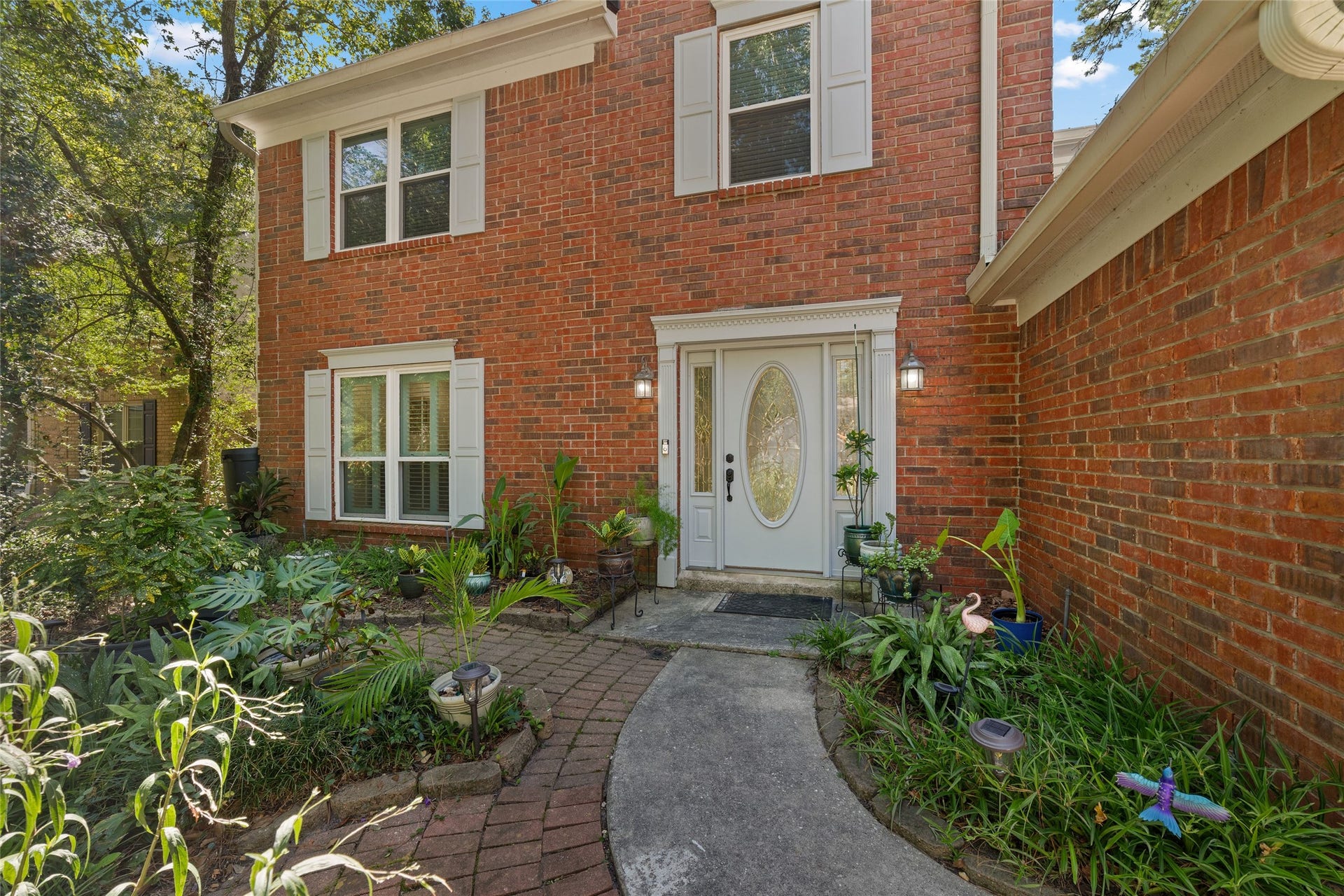218 E Rainbow Ridge Circle, The Woodlands, TX 77381 Lush landscaping greets you as you approach this charming brick home, offering a warm and inviting atmosphere.
