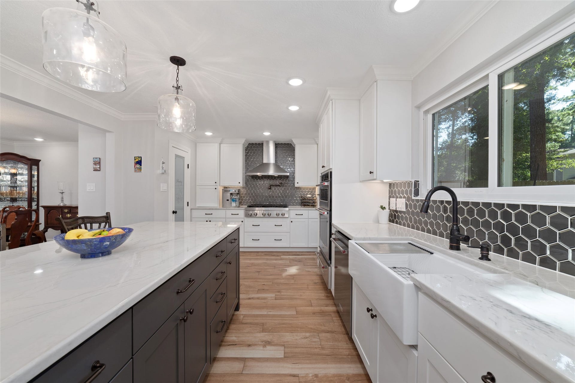 218 E Rainbow Ridge Circle, The Woodlands, TX 77381 Sleek, modern kitchen featuring a spacious island with elegant countertops, stainless steel appliances, and a stylish tile backsplash. Abundant natural light floods the space through large windows, creating an inviting atmosphere.