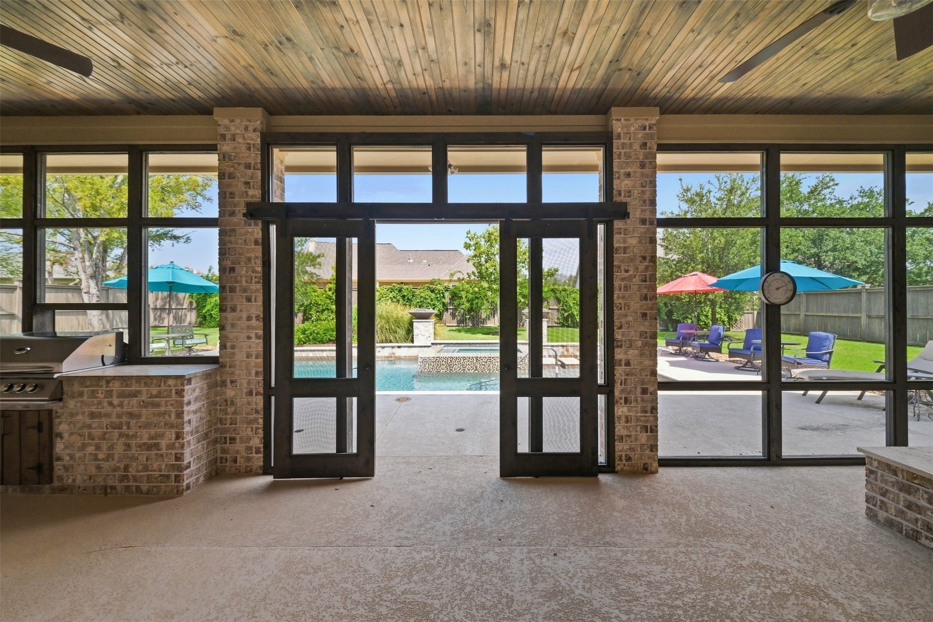 5117 Inverness Drive, Bryan, TX 77802 Expansive screened-in porch with a stained wood ceiling and ceiling fans opens directly to the pool, with the outdoor kitchen and fire pit just steps away.