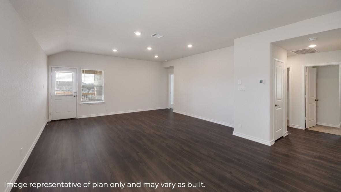 3831 Turnpike Drive, Fulshear, TX 77441 Spacious open-concept living area with sleek dark wood flooring, recessed lighting, and ample natural light from large windows and a door leading outside.