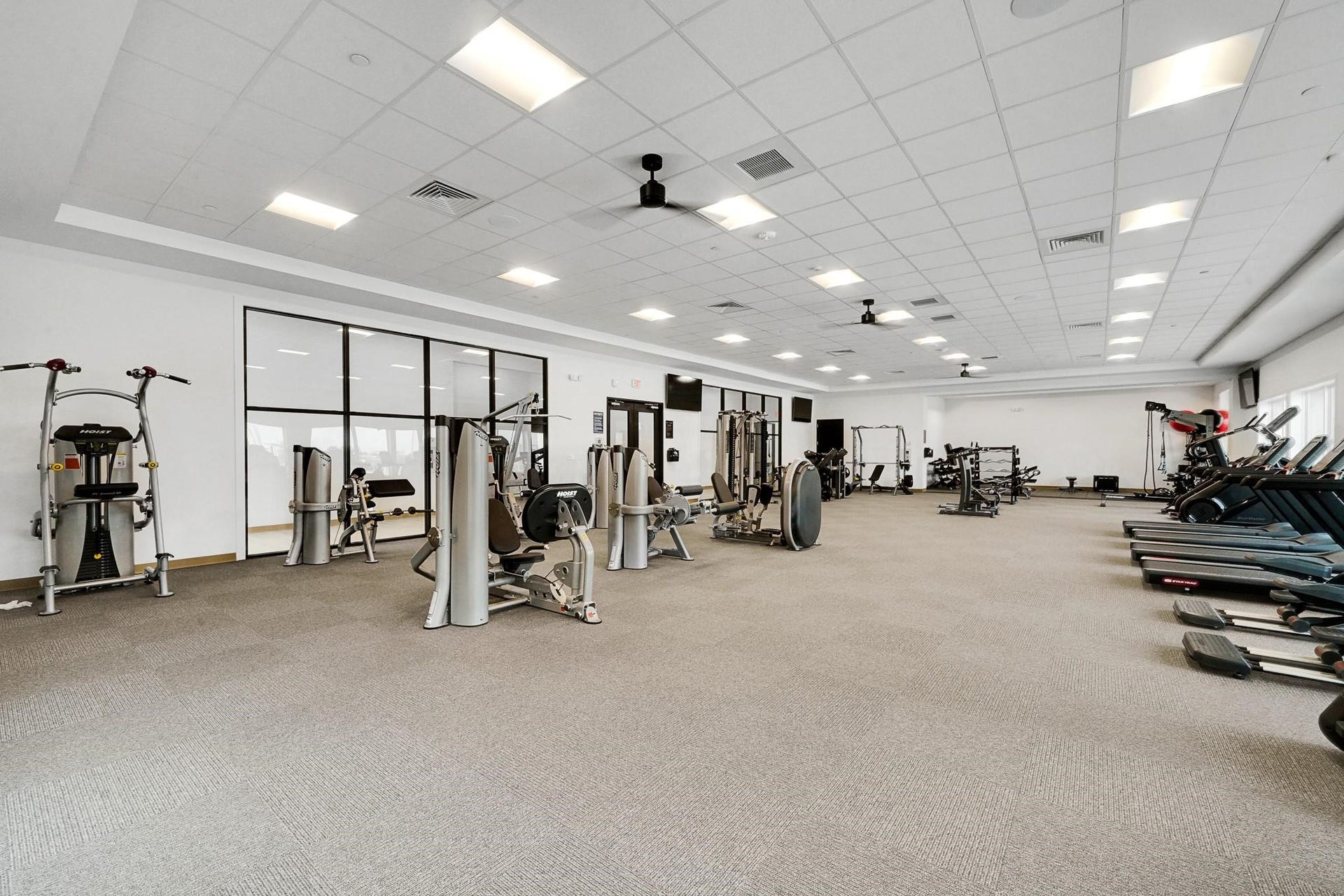 3831 Turnpike Drive, Fulshear, TX 77441 Spacious and well-equipped fitness center featuring a variety of exercise machines and ample natural light, perfect for maintaining an active lifestyle.