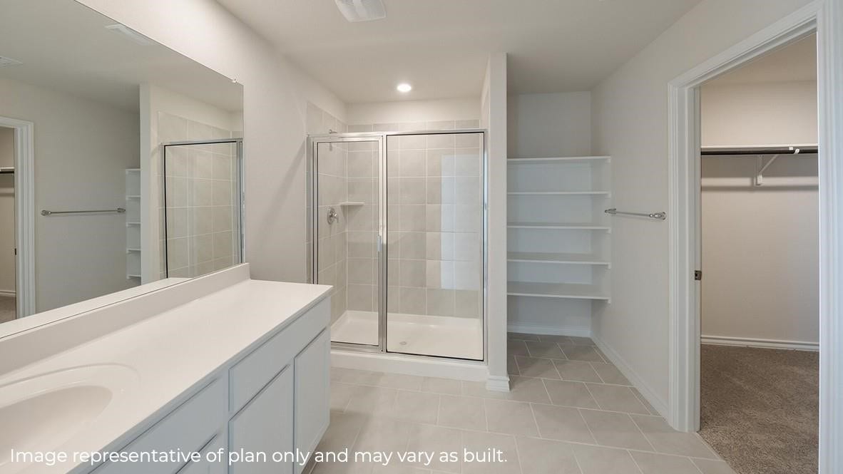 3831 Turnpike Drive, Fulshear, TX 77441 Spacious bathroom featuring a large walk-in shower, dual vanity, and convenient shelving, leading to a generous walk-in closet.