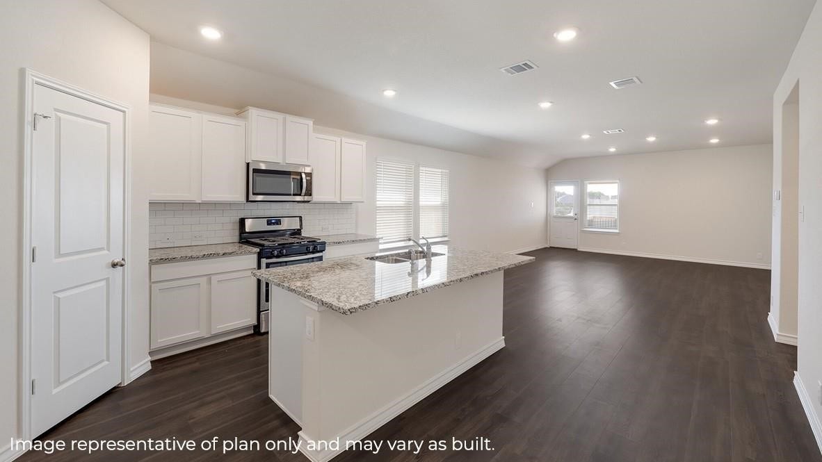 3831 Turnpike Drive, Fulshear, TX 77441 Spacious open-concept kitchen and living area featuring sleek dark wood flooring, modern white cabinetry, granite countertops, and stainless steel appliances.