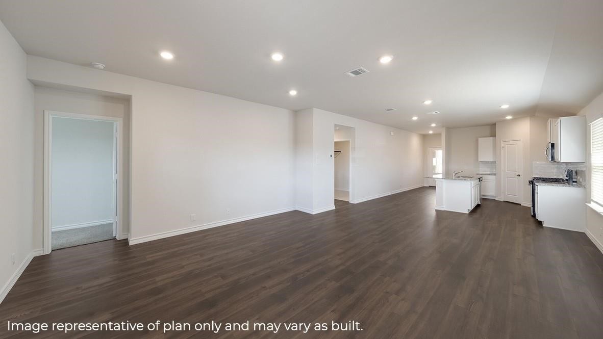 3831 Turnpike Drive, Fulshear, TX 77441 Spacious open-concept living area with elegant wood flooring, modern recessed lighting, and a bright kitchen featuring sleek countertops and ample cabinetry.