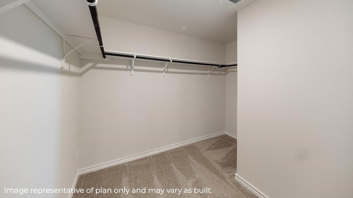 3831 Turnpike Drive, Fulshear, TX 77441 Spacious walk-in closet featuring ample hanging space and plush carpeting, perfect for organized storage.