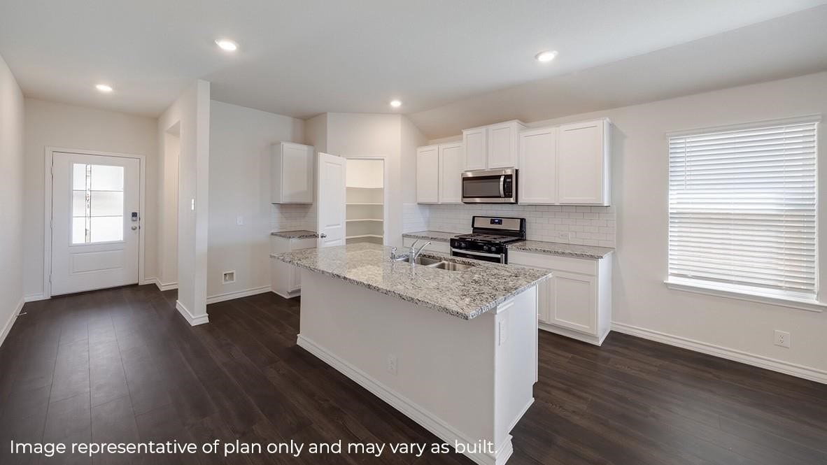 3831 Turnpike Drive, Fulshear, TX 77441 Bright and modern kitchen with sleek granite countertops, stainless steel appliances, and ample white cabinetry, complemented by dark wood flooring and natural light.