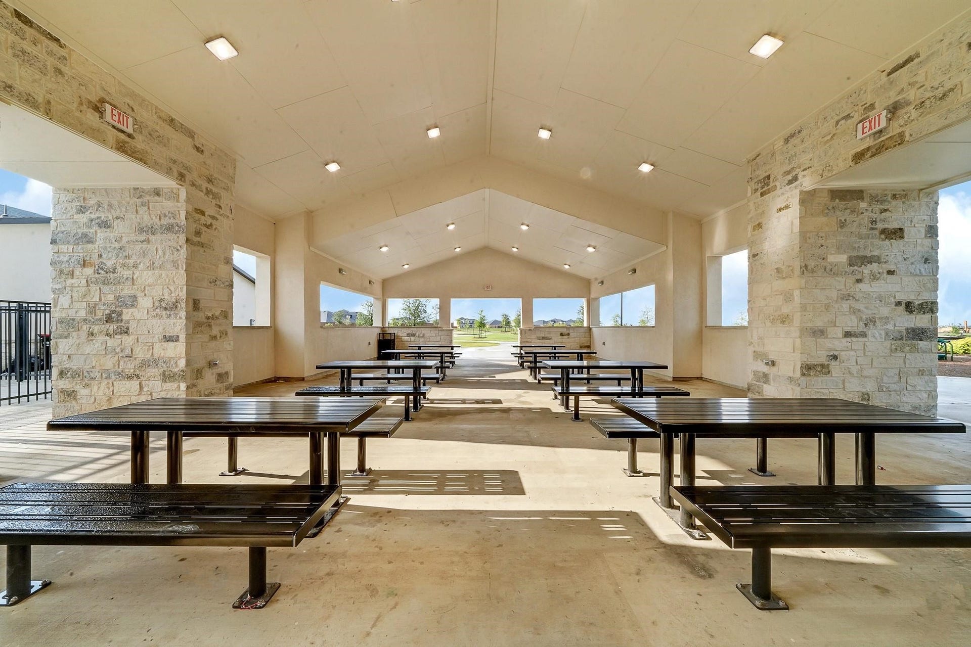 3831 Turnpike Drive, Fulshear, TX 77441 Spacious covered pavilion with sturdy picnic tables and stone accents, ideal for gatherings and enjoying outdoor views.