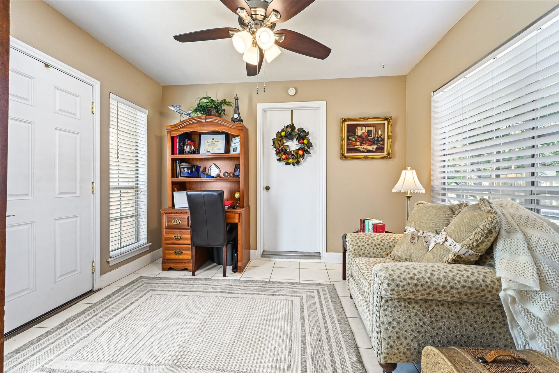 25803 Maplewood Drive, Spring, TX 77386 Charming and cozy sitting area features a plush armchair, a classic wooden desk with built-in shelves, and ample natural light from large windows, creating a warm and inviting space.