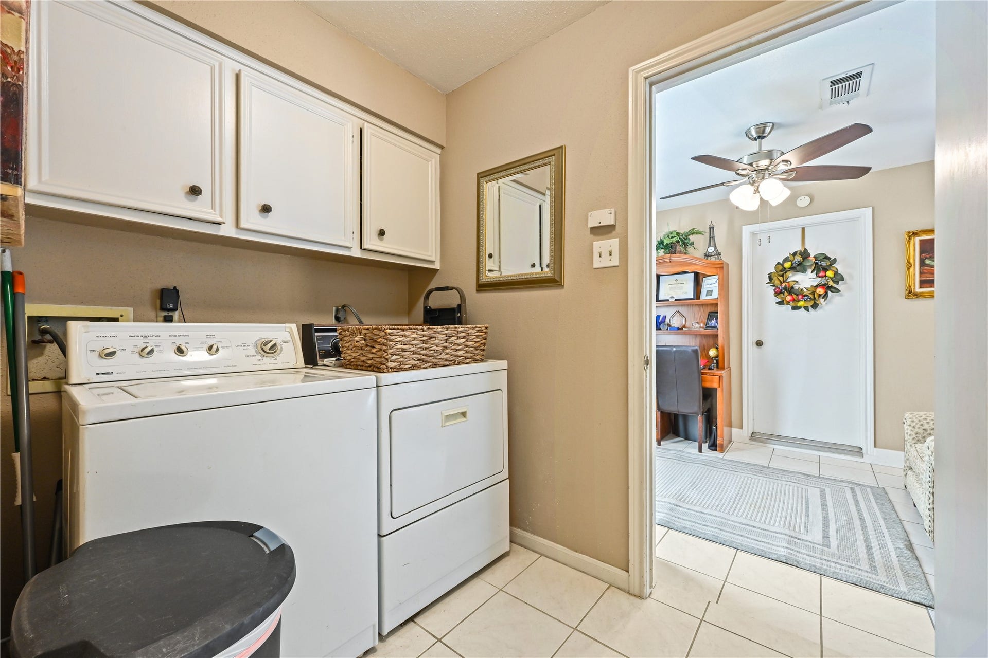 25803 Maplewood Drive, Spring, TX 77386 Convenient laundry room equipped with a washer and dryer, ample cabinetry for storage, and easy access to an adjoining room with a ceiling fan and office nook.