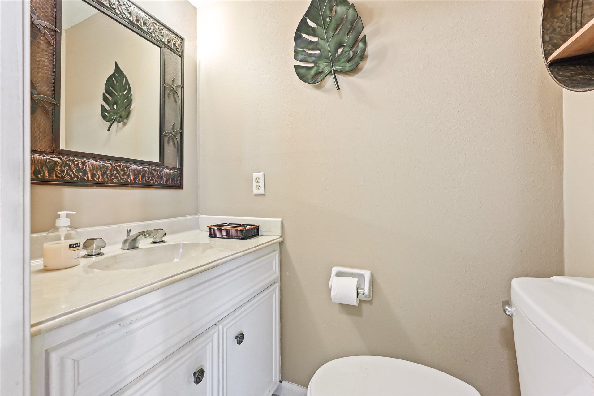 25803 Maplewood Drive, Spring, TX 77386 Charming powder room with a sleek vanity, elegant mirror, and tasteful tropical decor accents.